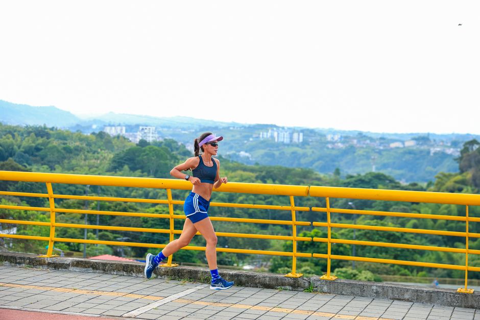 Woman running along a city bridge with scenic views. Outdoor fitness activity.